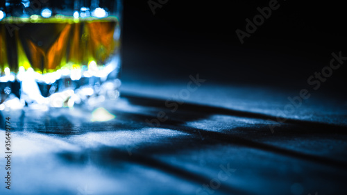 Photography Blurred background, whiskey in a glass with edges lit by a ray of bright light,