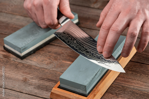 Man sharpens a Gyuto knife using a whetstone photo