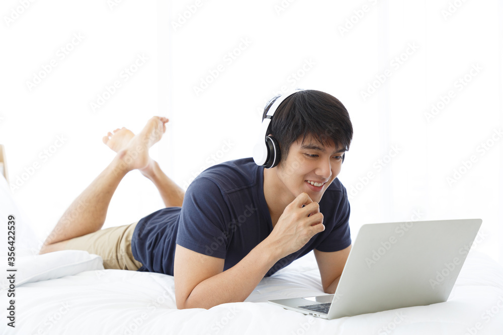 Happy man using Laptop computer and checking good News in the Bedroom. COPY SPACE. Trading. Watching Movie. WORK FROM HOME WFH Concept. Happy man using Laptop computer and checking good News in the Bedroom. COPY SPACE. Trading. Watching Movie. WORK FROM HOME WFH Concept.