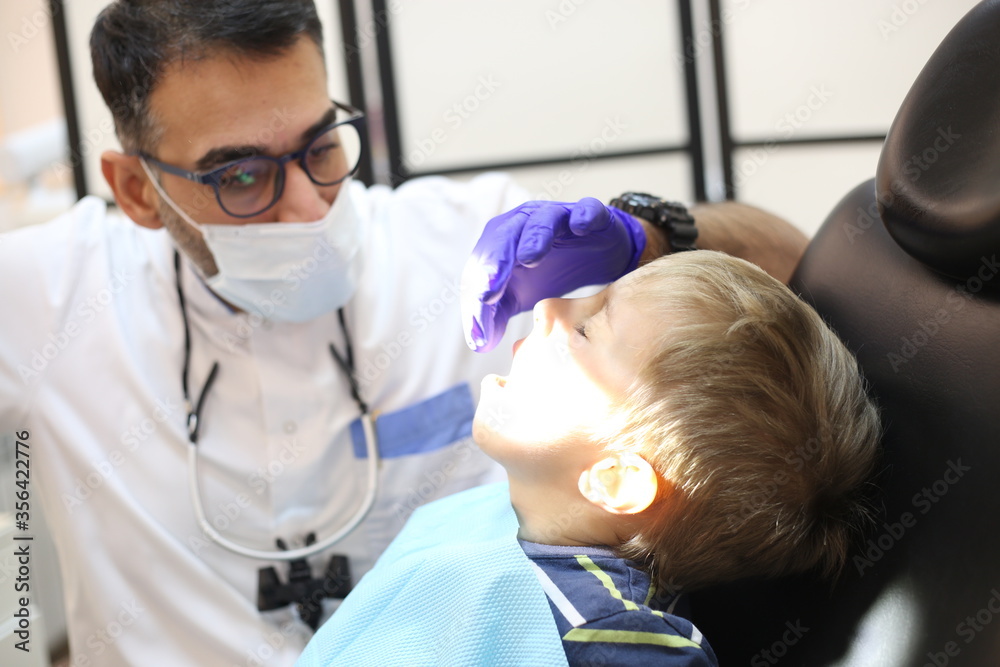 dentist is diagnosing the child while assistant in dental clinic