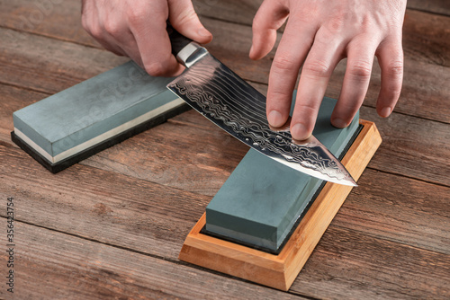 Man sharpening a Japanese chef's knife with a wet whetstone photo