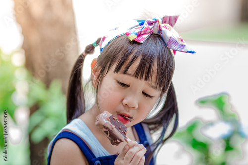 Close up background view Of ASEAN girls eating delicious ice cream, with chocolate flowing on clothes, the concept of self-learning