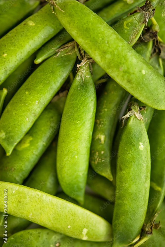 Vertical picture with selective focus on fresh bright green pea pods. Organic food. Antioxidant, natural, vitamin, organic, vegetarian food. Macro background.