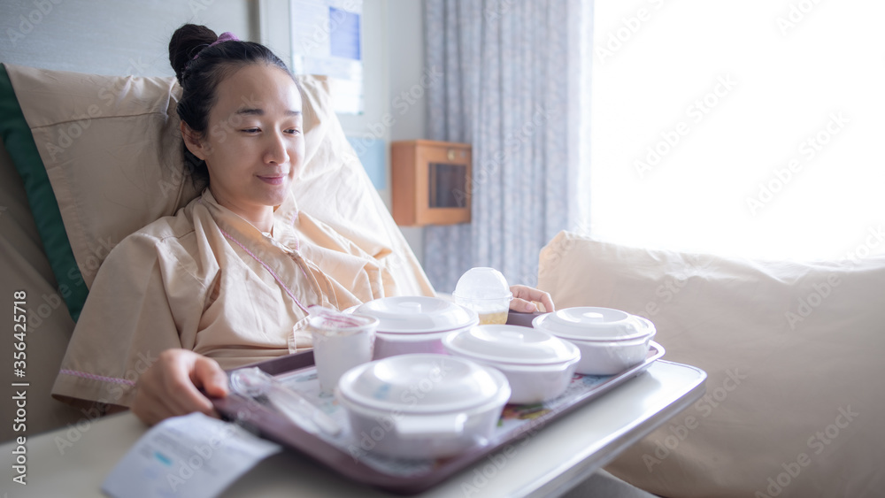 Asian woman lying on the hospital bed for admitting and she is ating breakfast. Hospitalization concept. Asian woman lying on the hospital bed for admitting and she is ating breakfast. Hospitalization concept.
