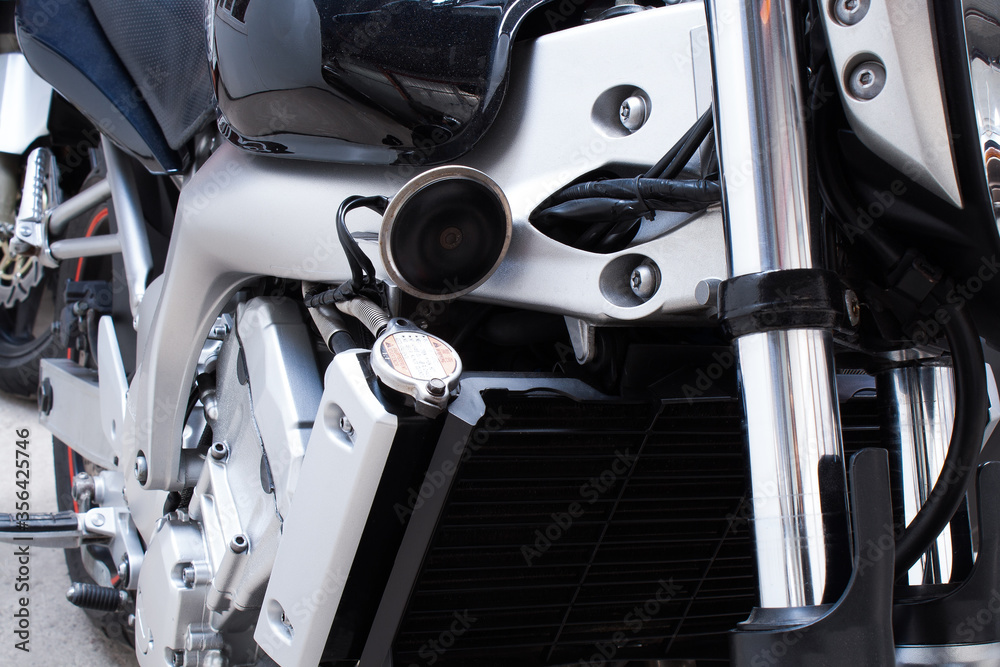 Close-up of air filter, radiator, chrome frame of motorcycle. Water, liquid cooling, front fork, signal, tank, sport bike engine in the workshop. Color photo from a low angle of a road bike in garage