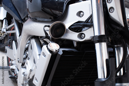 Close-up of air filter, radiator, chrome frame of motorcycle. Water, liquid cooling, front fork, signal, tank, sport bike engine in the workshop. Color photo from a low angle of a road bike in garage © Maksim