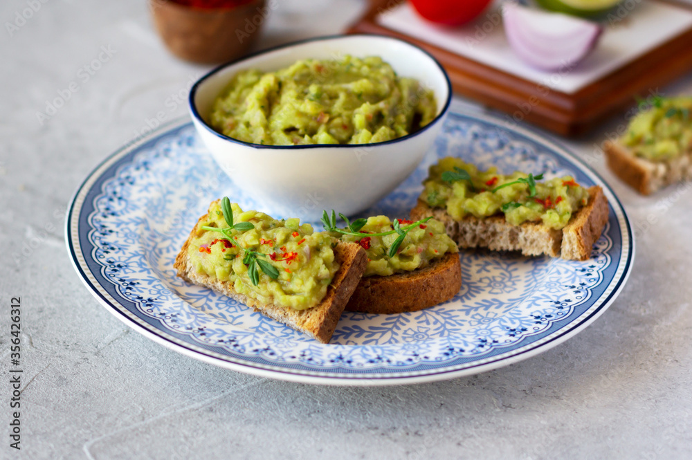 Guacamole dip and toasts on a plate and ingredients. Mexican  cuisine