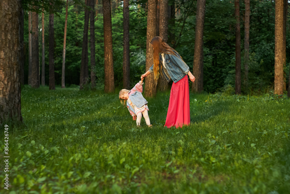 woman with little daughter dance on the lawn in the park woman with little daughter dance on the lawn in the park