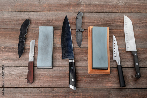 Assortment of knives and whetstones on rustic wooden background, top view photo