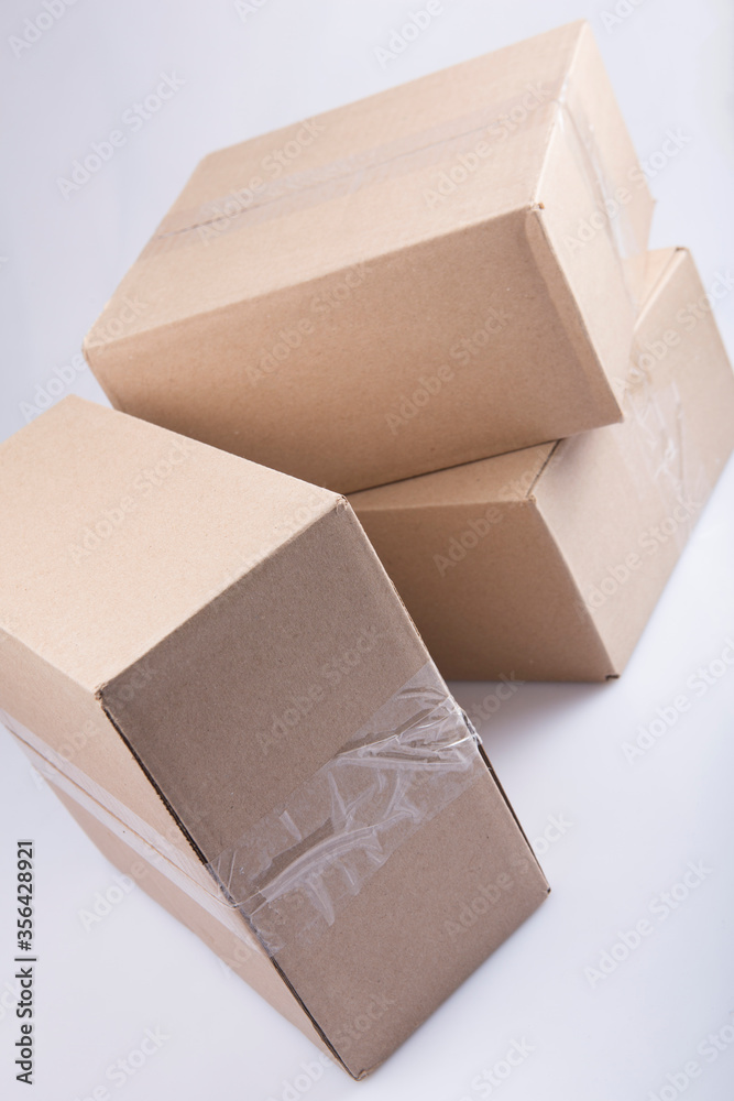 isolated close up shot of three stacked closed rectangular blank brown carton cardboard boxes on a white background isolated close up shot of three stacked closed rectangular blank brown carton cardboard boxes on a white background