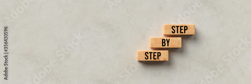 cubes with message STEP BY STEP on concrete background