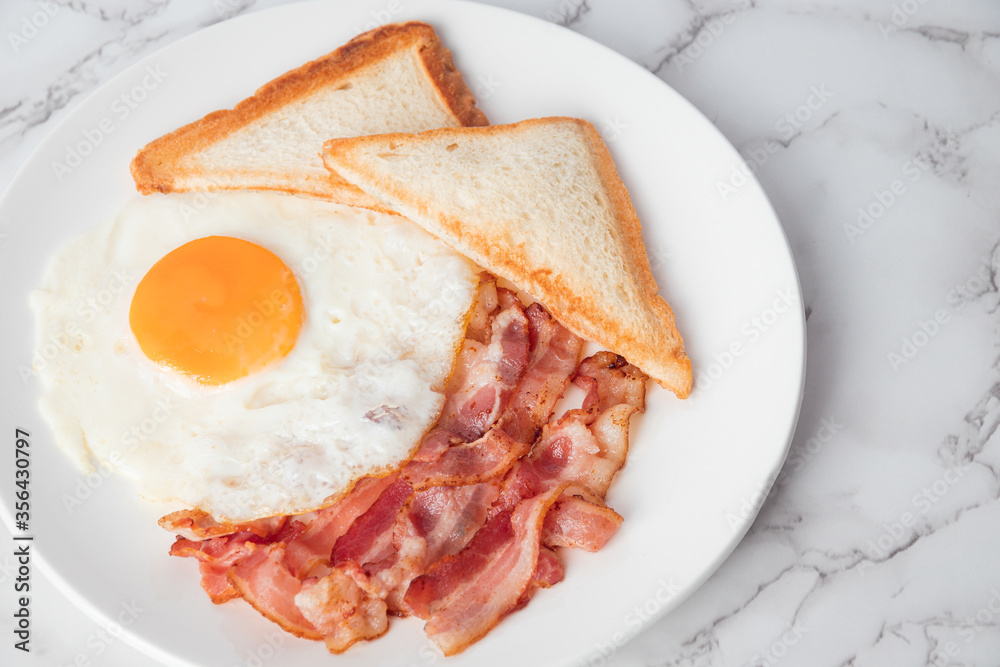 Close up breakfast with sunny side eggs, bacon and toast bread on a plate Close up breakfast with sunny side eggs, bacon and toast bread on a plate