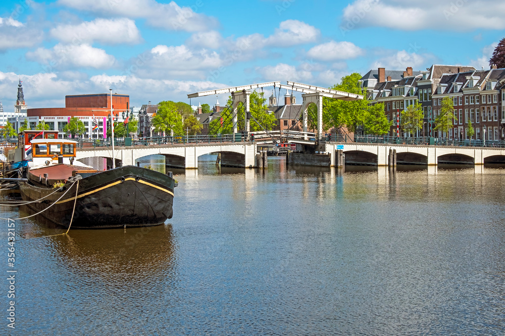 City scenic from Amsterdam at the river Amstel in the Netherlands with the Tiny Bridge