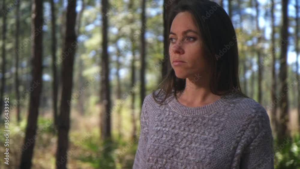 Close up orbit of girl looking around, thinking, possibly lost in pine forest