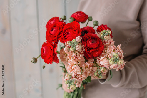 Amazing bouquet of red peonies and flowers for the bride for the wedding in the hands of a girl