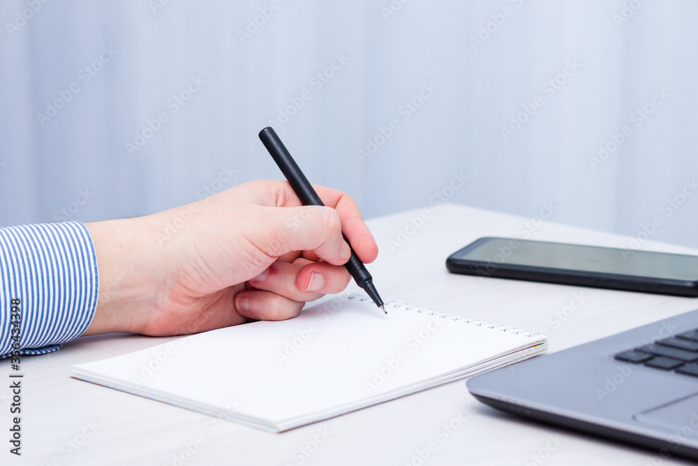 Left-handed man writes in a notebook. Left hander day concept. Left-handed man writes in a notebook. Left hander day concept.