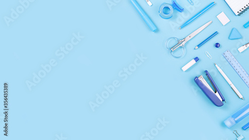 Assorted office and school white and blue stationery on pastel background as border. Flat lay knolling with copy space for back to school or education and craft concept. Blue monochrome banner