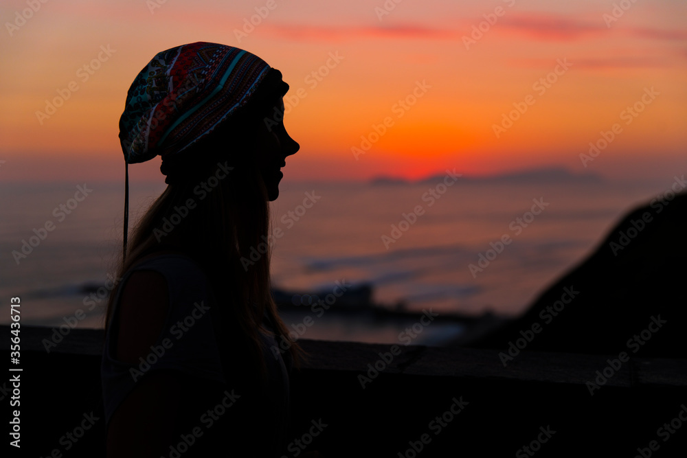 woman looking the sunset in a city with beach