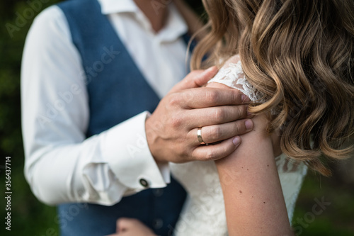 The man holds a woman by the shoulder. Wedding ring on a man's finger