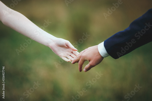 Close-up of bride?s hand holding that of her husband over green background © Владислав Васильчук