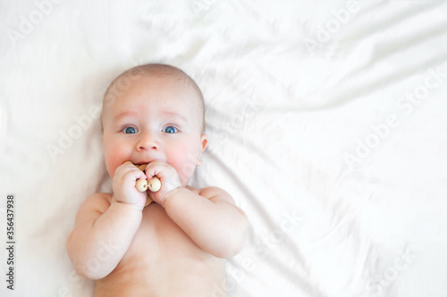Cute happy baby playing with wooden eco beads on white background