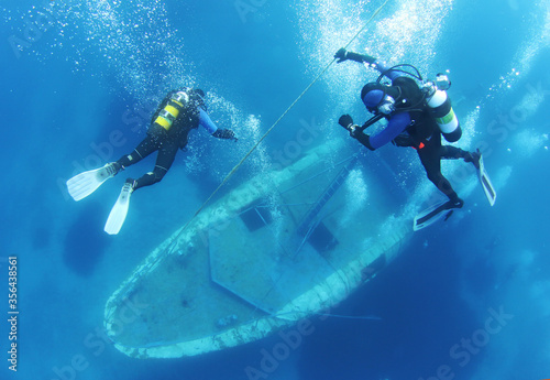 Fotografie, Obraz Scuba Divers go down the rope and Exploring underwater ship wreck