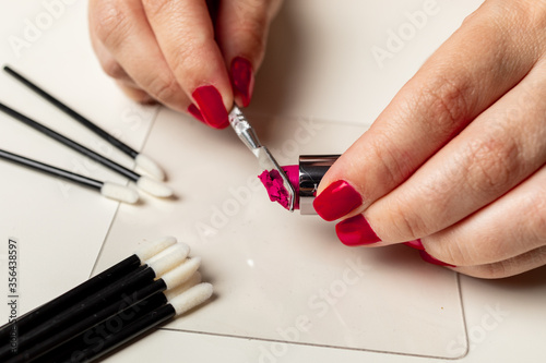 Woman s hands cutting lipstick to apply hygienic makeup on palette and disposable material.
