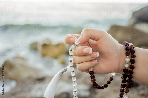 Woman hand holding japa mala. Mantra meditation technique by the sea. Hinduism and buddhism photo