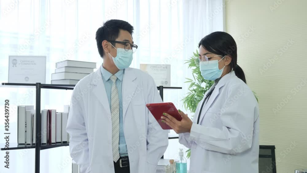 Asian Doctors wear mask and using digital tablet modern technology in medicine and healthcare, New Normal and Social Distancing concept Asian Doctors wear mask and using digital tablet modern technology in medicine and healthcare, New Normal and Social Distancing concept