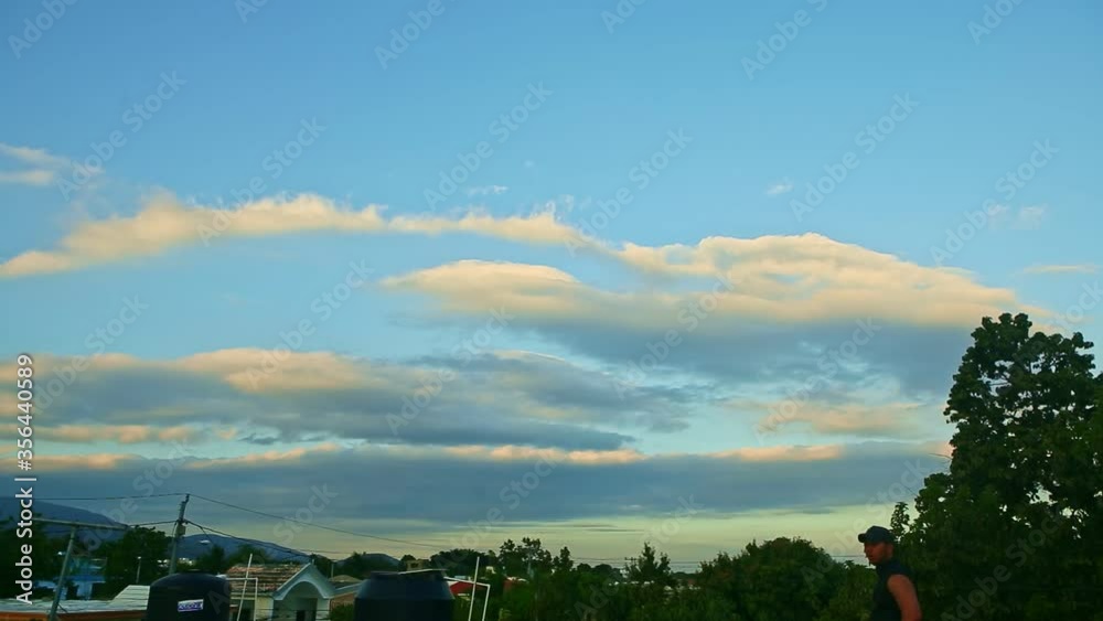 large fluffy white clouds float on blue sky above small tropical city house roofs large fluffy white clouds float on blue sky above small tropical city house roofs