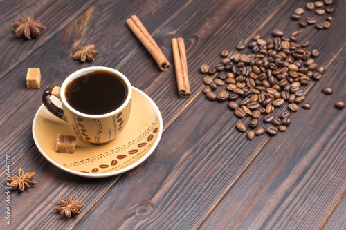 Cup of coffee. Coffee beans scattered on table, star anise, cinnamon sticks