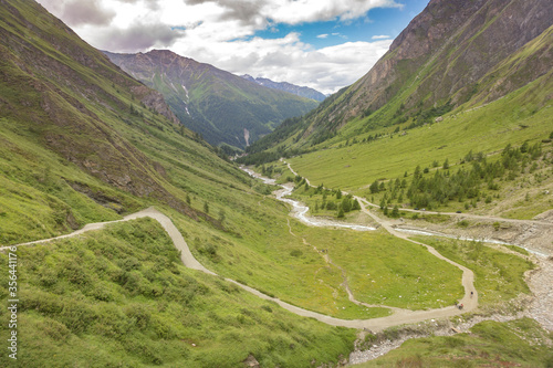 Mountain river, tourist route and a green valley between the mountains in Austrian Alps. View from the way to Grossglockner rock summit, Kals am Grossglockner, Austria