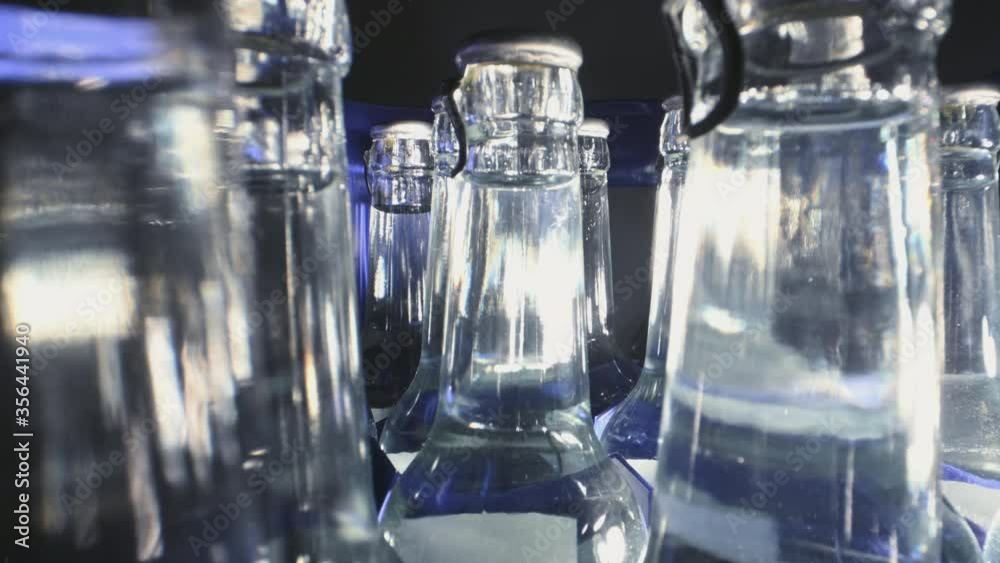 Transparent Glass Bottles In Close Up View Filled With Mineral Water Placed In Blue Plastic Container. Transparent Glass Bottles In Close Up View Filled With Mineral Water Placed In Blue Plastic Container.