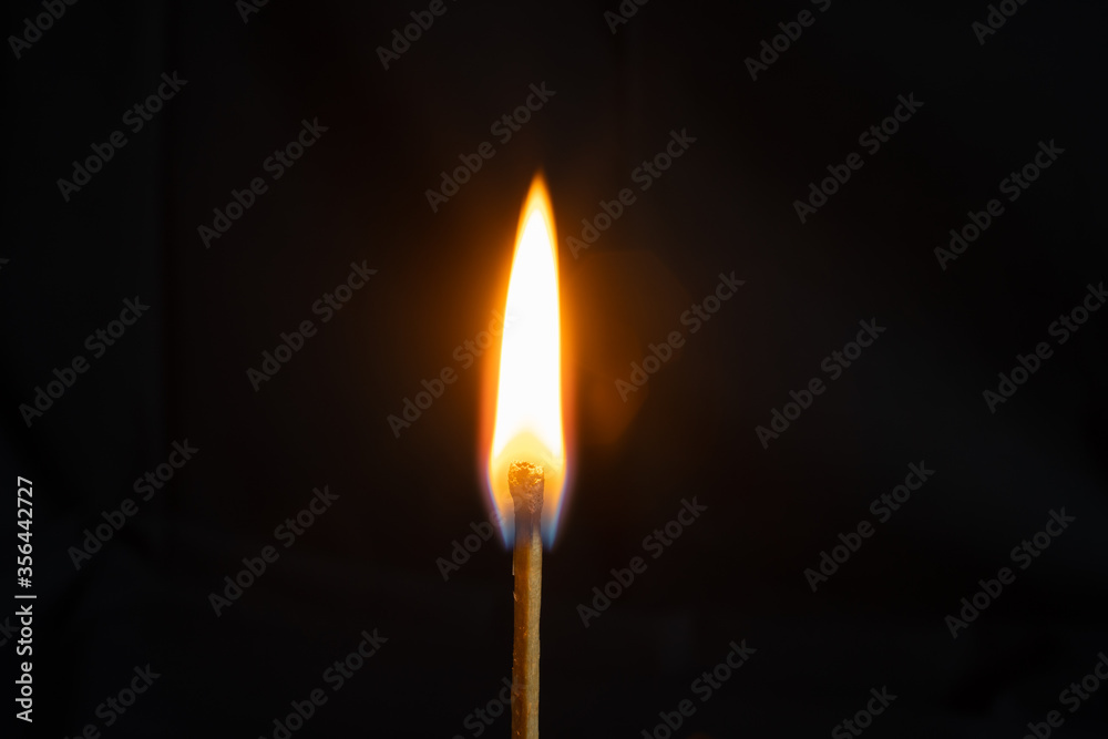 Low key, close up burning matchstick on black background with bokeh Low key, close up burning matchstick on black background with bokeh