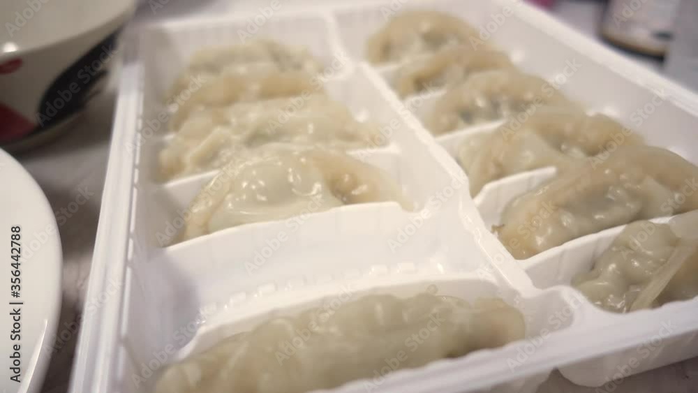 People using silver fork Gyoza in a plastic tray People using silver fork Gyoza in a plastic tray