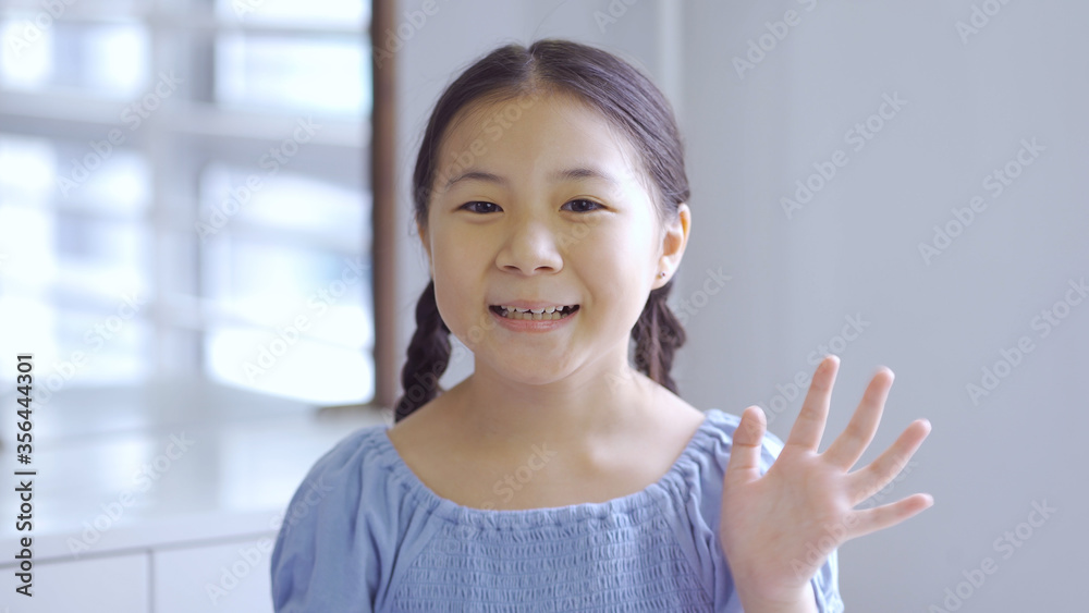 Cute asian little girl smiling and waving hand Cute asian little girl smiling and waving hand