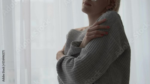 Wallpaper Mural Happy lady in cozy knitted sweater standing by window, hugging herself, smiling Torontodigital.ca