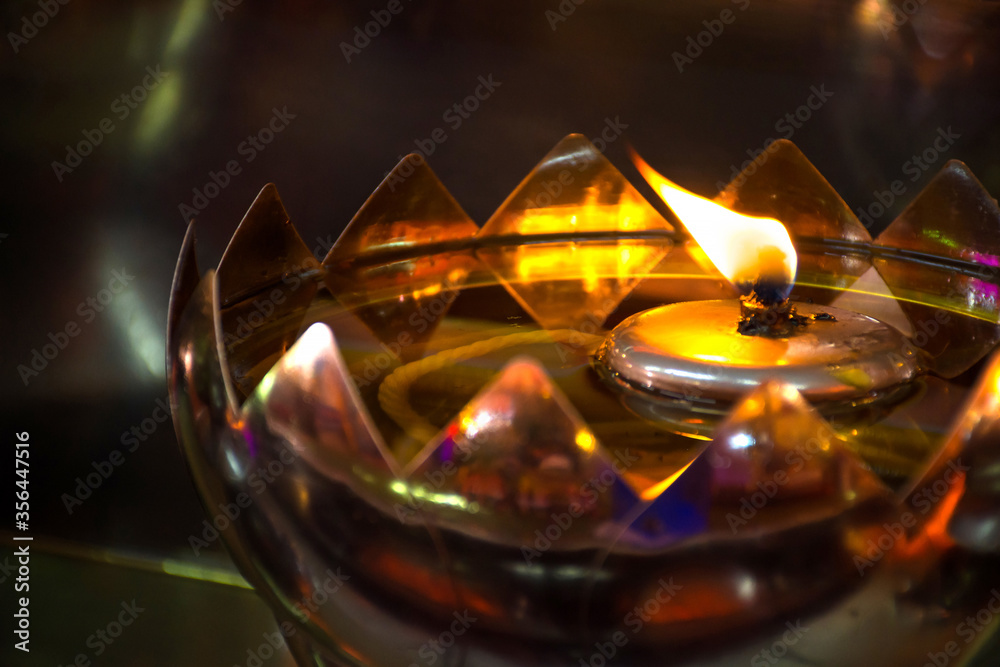 Fire burning on oil lamp in temple in aluminum bowl.
