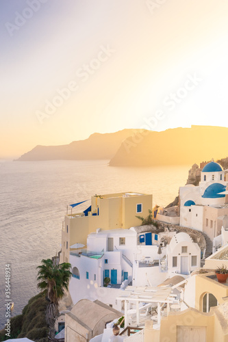 Sunset view of Oia with blue domes ( Saint Nikolaos Peramataris )and bell tower, Thirasia in the back, Santorini island, Cyclades, Greece 