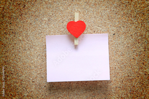pink paper on a wooden background with heart clip for love concept