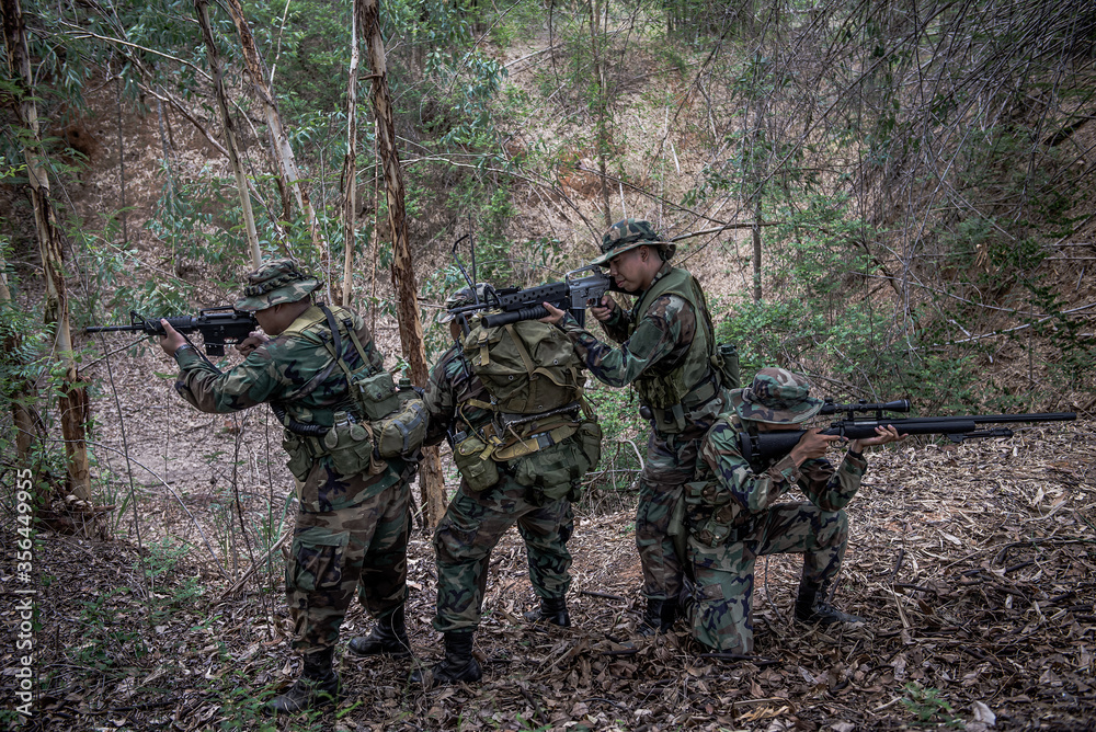 Team of army soldier with machine gun moving in the forest,Thai militia soldier in combat uniforms in the wood,Wander the patrol sloping in the rainforest. Team of army soldier with machine gun moving in the forest,Thai militia soldier in combat uniforms in the wood,Wander the patrol sloping in the rainforest.