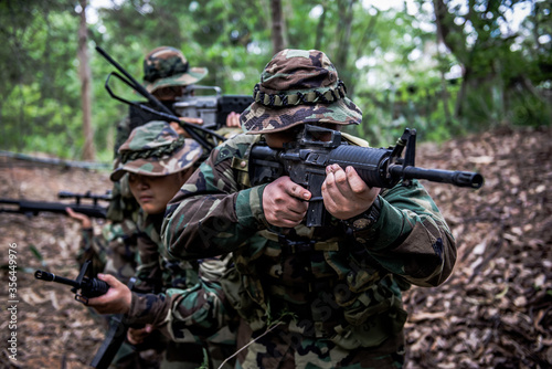 Photography Team of army soldier with machine gun moving in the forest,Thai militia soldier in combat uniforms in the wood,Wander the patrol sloping in the rainforest