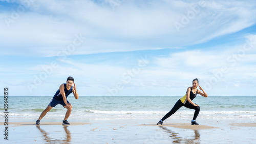 Asian couples leave some distancing between exercising or stretching before exercising in the morning by the sea.