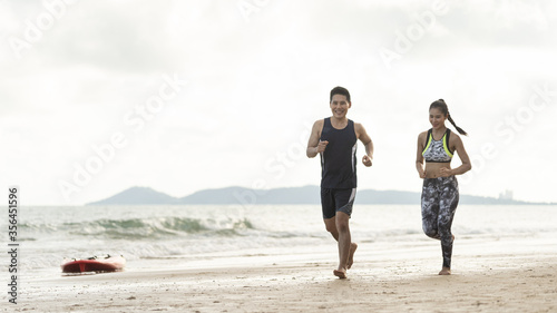 Healthy Asian couples jogging on the seaside in summer on weekend or outdoor exercise after unlocking down from COVID 19