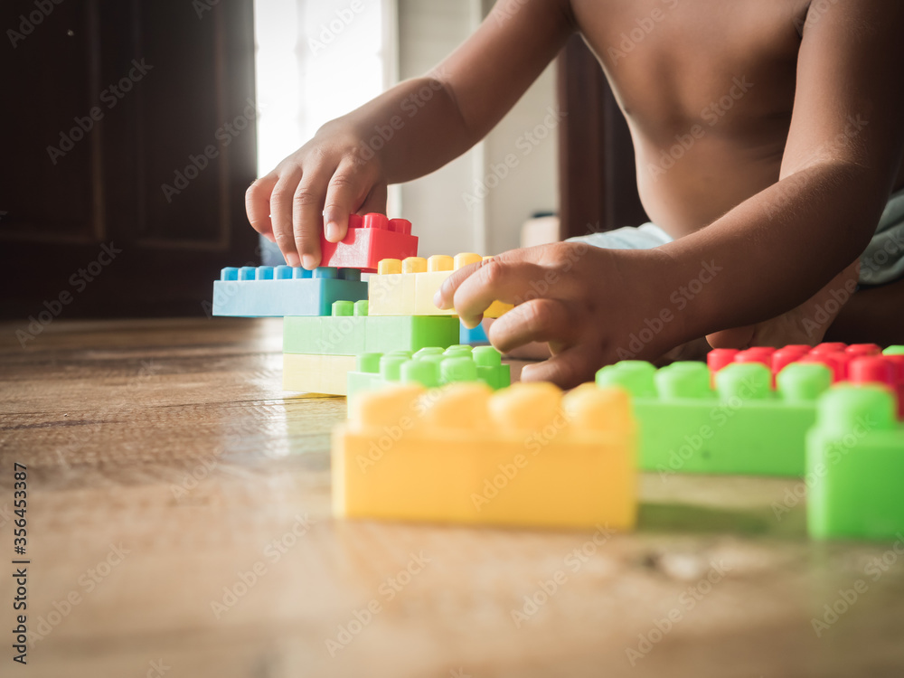Dark-skinned Asian children are playing blocks at the wooden floor. Learning and development of children Dark-skinned Asian children are playing blocks at the wooden floor. Learning and development of children