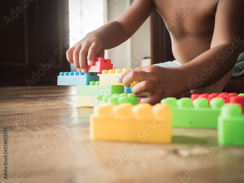 Dark-skinned Asian children are playing blocks at the wooden floor. Learning and development of children