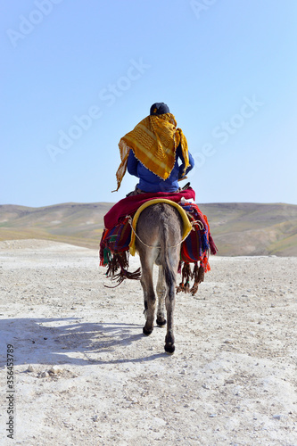 arabian man riding donkey in the desert 