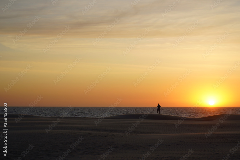Person watching a beautiful sunset at the beach in Koksijde on a summer day