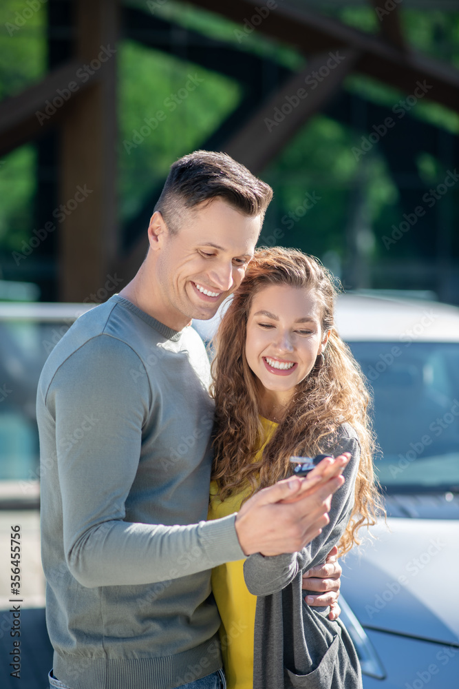 Loving man and woman standing embracing looking at the key. Loving man and woman standing embracing looking at the key.