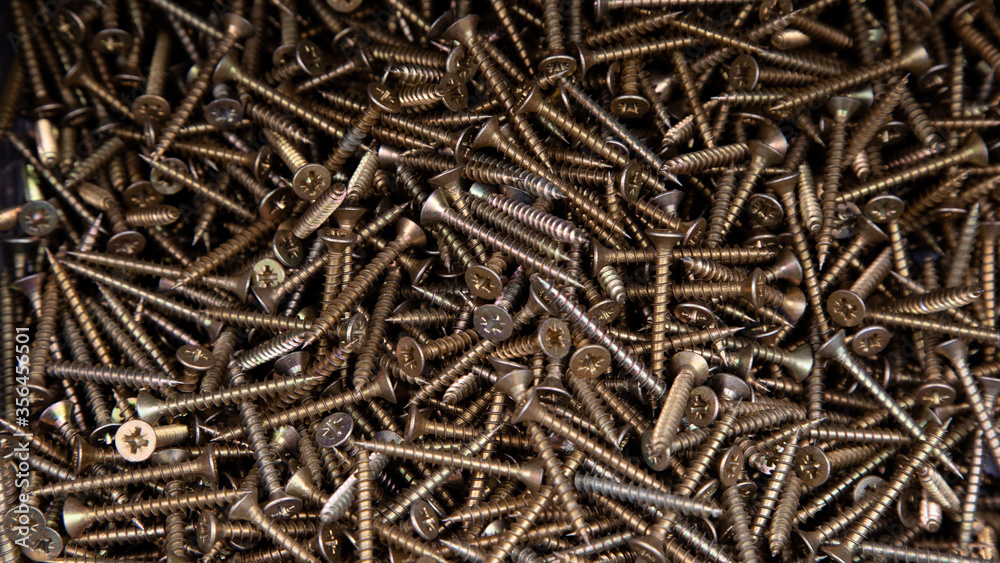 Macro of bronze self-tapping screws for wood working. Strong screws on a wooden table Macro of bronze self-tapping screws for wood working. Strong screws on a wooden table